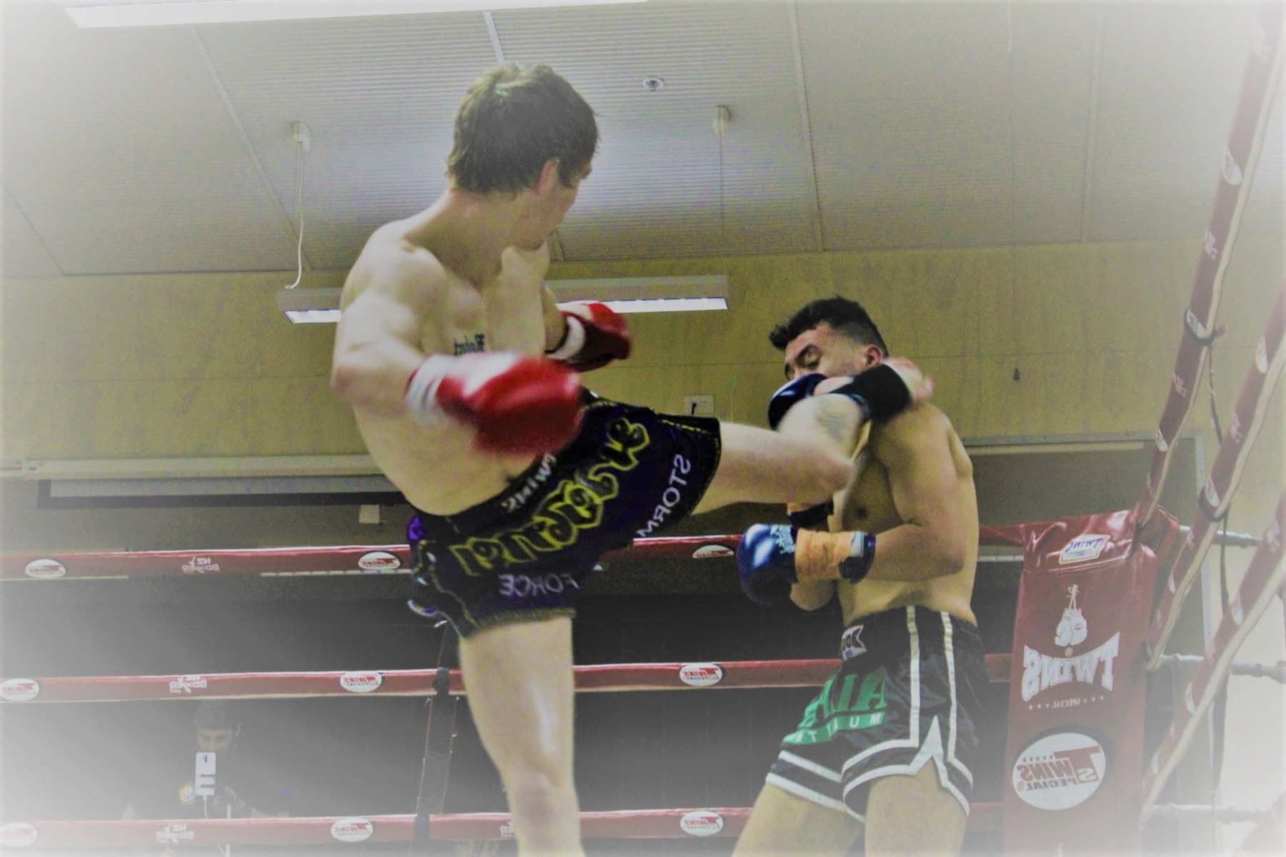 Two kickboxers exchanging a body kick during a ring bout